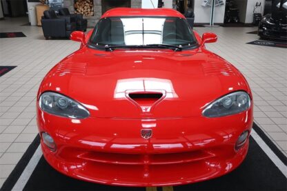 A red 1997 Dodge Viper GTS is parked in a showroom.