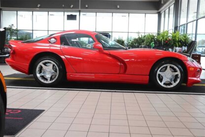 A red sports car is parked in a showroom.