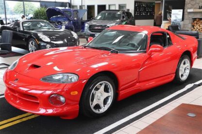 A 1997 Dodge Viper GTS, a red sports car, is parked in the showroom.