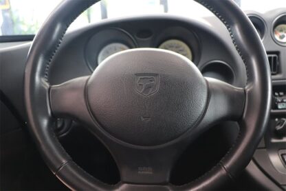 The steering wheel of a black car.