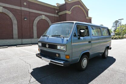 A blue Volkswagen bus parked in a parking lot.