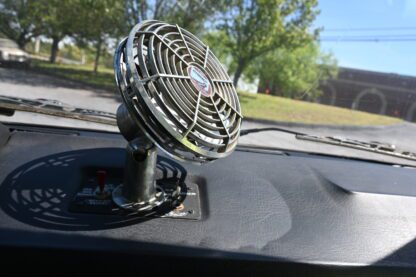 A fan on the dashboard of a car.