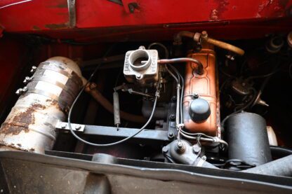 The engine compartment of an old red car.