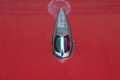 A close up of the hood ornament on a red car.