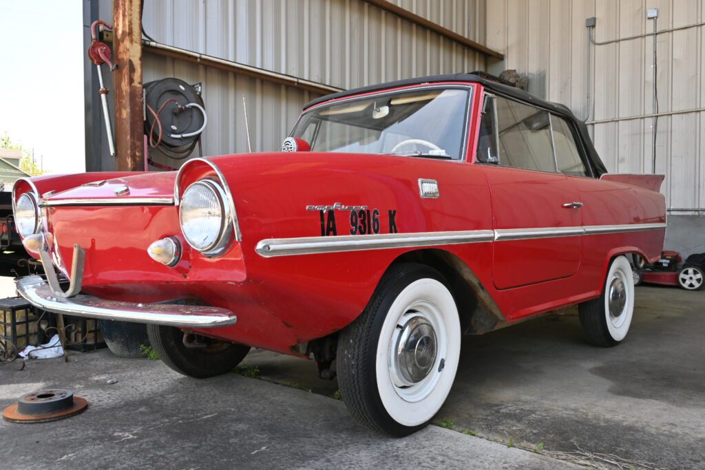 An old red and white car parked in a garage.