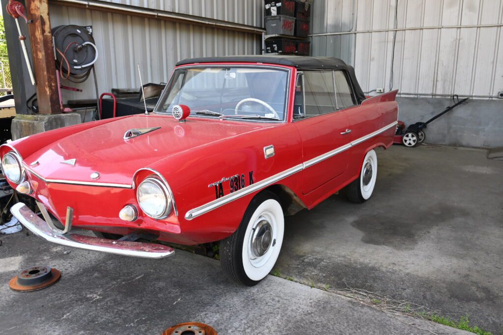 An old red car parked in a garage.